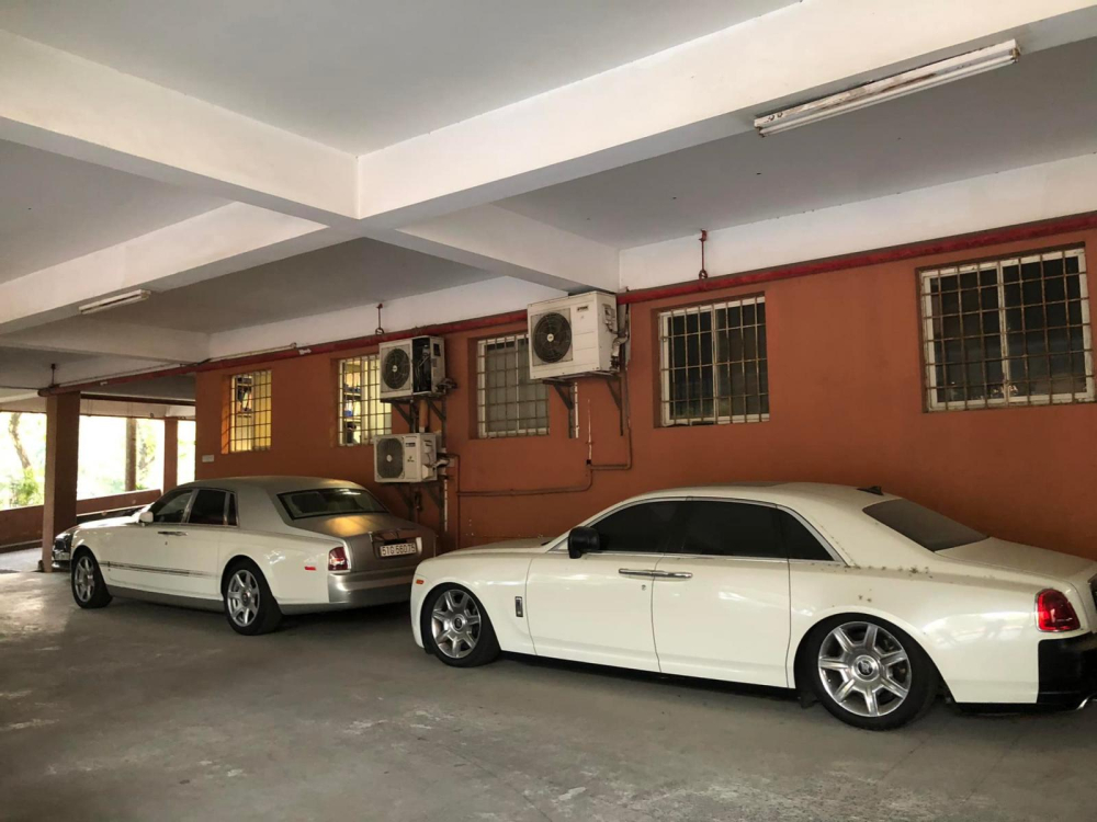 Hình ảnh chiếc xe siêu sang Rolls-Royce Phantom màu bạc dán thêm đề-can trắng và chiếc xe siêu sang Rolls-Royce Ghost màu đen trắng bám bụi cùng với phuộc xe bị hỏng bóng hơi