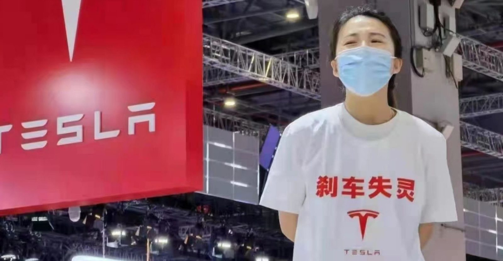 Người phụ nữ mặc &aacute;o in d&ograve;ng chữ Hỏng phanh v&agrave; logo Tesla