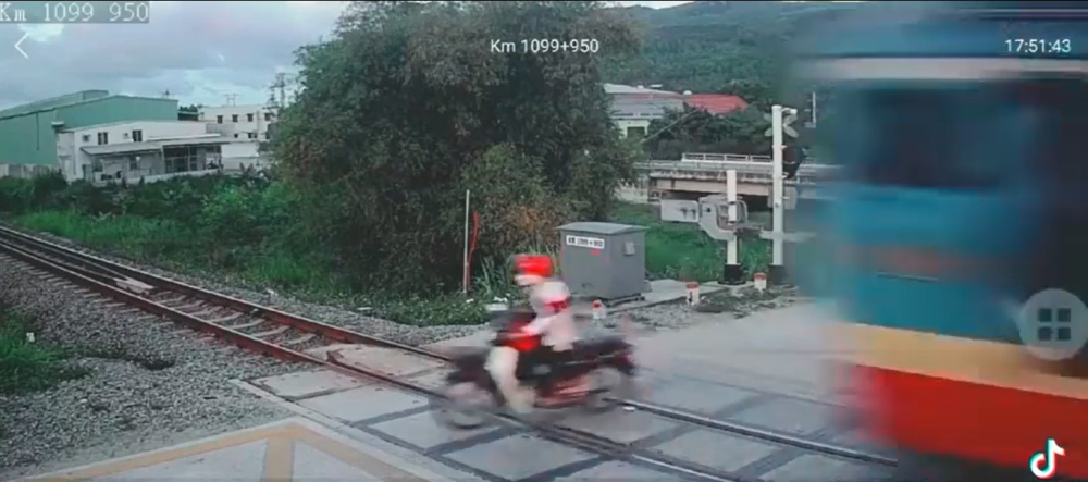 Bất chấp rào chắn đã hạ xuống và đèn tín hiệu cảnh báo, thanh niên đi xe máy vẫn băng qua đường ray, đúng lúc tàu hỏa lao đến