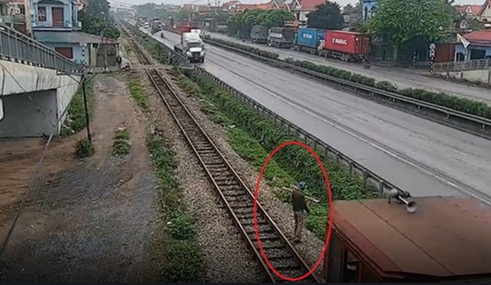 Người đ&agrave;n &ocirc;ng vượt r&agrave;o chắn, đứng cạnh đường ray t&agrave;u hỏa