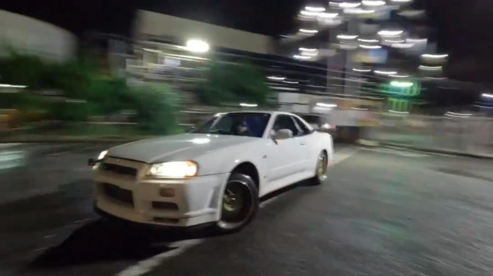 Hamilton đốt lốp chiếc Nissan Skyline R34 GT-R trong một bãi đỗ xe không người Hamilton đốt lốp chiếc Nissan Skyline R34 GT-R trong một bãi đỗ xe không người