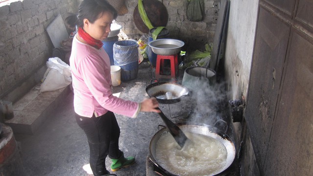 Chị Gấm đều tay đảo nha v&agrave; đường tr&ecirc;n bếp lửa.