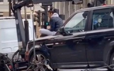 Cô gái "cố thủ" trên nắp ca-pô của chiếc SUV hạng sang Range Rover để ngăn cảnh sát cẩu xe đi
